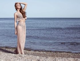 Bohem Elbise giyen ve Bohem Giyim Tarzına Sahip olan kadın Bozcaada sahilinde gün batımında yüzünü güneşe dönmüş otantik takıları ile poz vermekte
